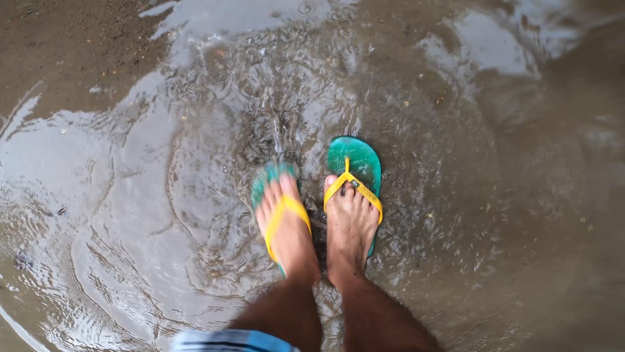 pies de un hombre remando en el agua de lluvia turbia - toma de ángulo alto
