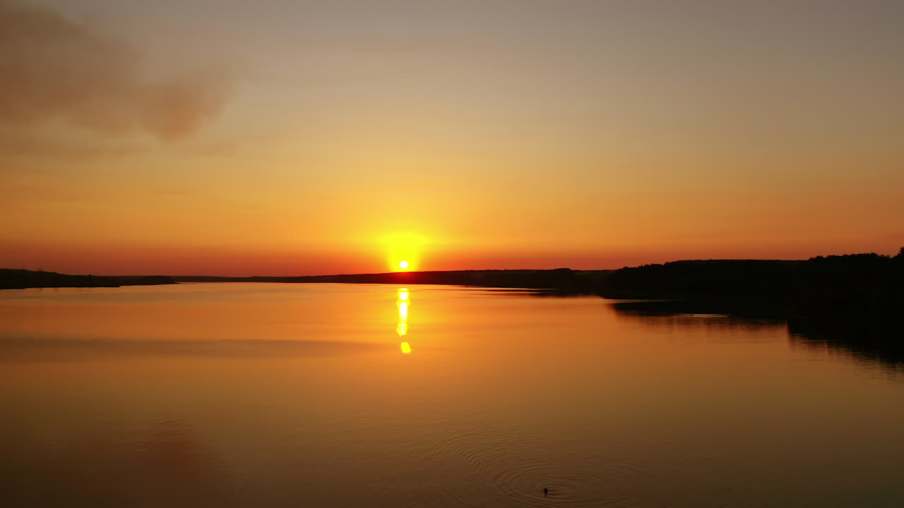 Beautiful sunset over the river. Amazing landscape of the evening water with the golden path from the setting sun. Wonderful lake at sunset. Motion camera to the left.