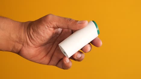 person holding a small white cylinder container