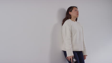 Stressed-Or-Anxious-Woman-Sitting-On-Floor-Leaning-Against-Wall-At-Home-Reacting-To-Internet-Or-Social-Media-News-Message-Or-Story-On-Mobile-Phone-7