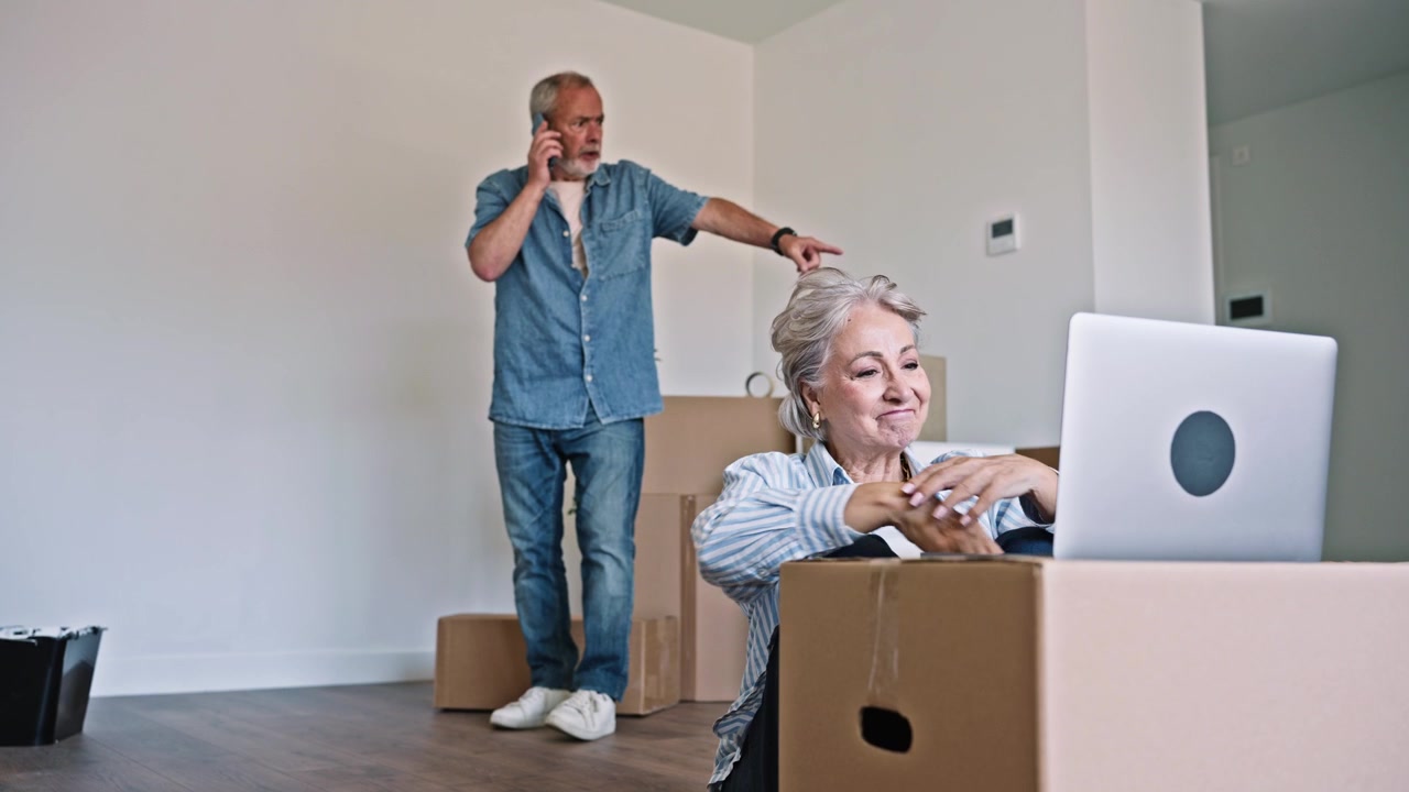 Senior Couple Organizing New Home with Laptop and Smartphone