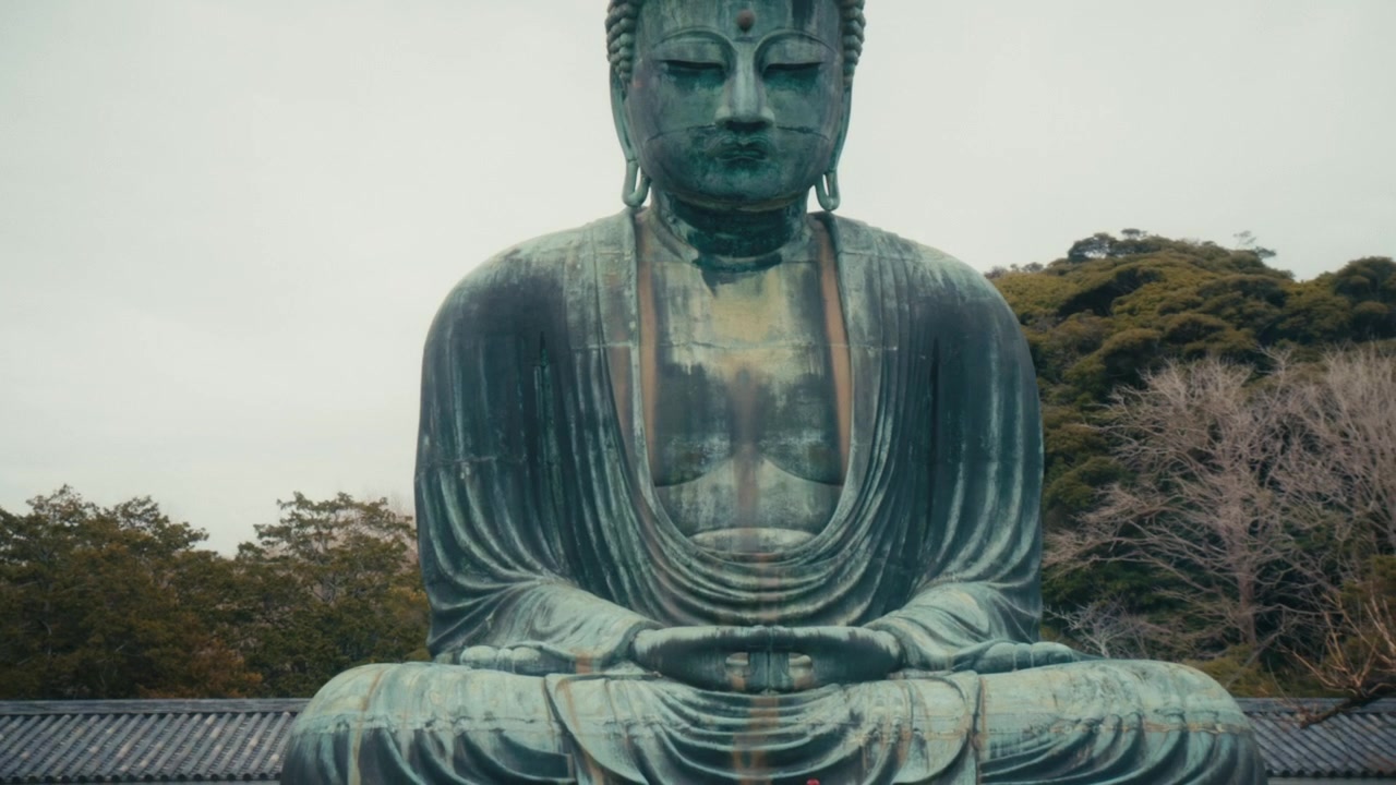 Vista frontale simmetrica del Grande Buddha (Daibutsu) presso il tempio Kotoku-in a Kamakura, che cattura l'espressione calma e meditativa della statua e il raffinato dettaglio scultoreo delle sue vesti drappeggiate