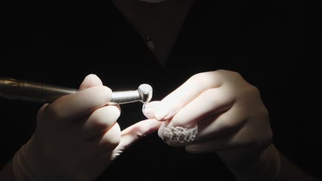 dental professional refining a clear aligner with precision tool under focused light