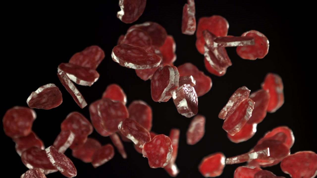 Salami Slices Falling in Slow Motion Against Black Background