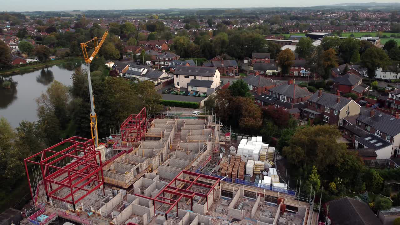 Establishing aerial view crane building waterside care home construction framework in rural British village next to fishing lake