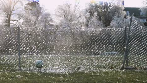 Cámara-Lenta:-Una-Pelota-De-Fútbol-Choca-Contra-Una-Valla-Helada-Que-Explota-El-Hielo-Roto-En-El-Aire