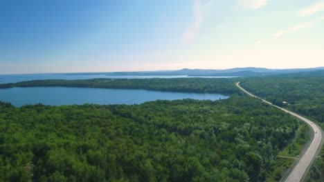 drone shot rising up revealing a massive lake next to a wooded highway