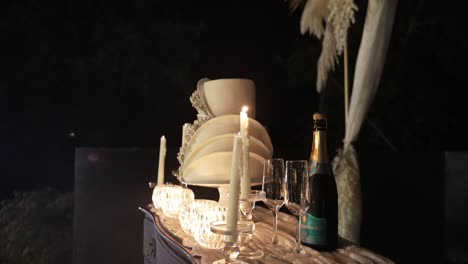 table with elegant decor including lit candles, champagne bottle, and a multi-tiered cake