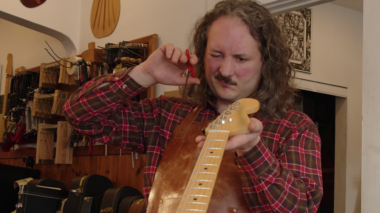 Tecnico in negozio regola il truss rod nel manico di una chitarra elettrica vintage.