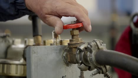 Engineer-worker-opens-hand-valve-faucet-tap-on-industrial-equipment-close-up