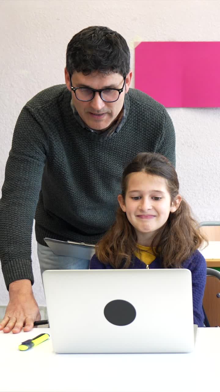 Child using laptop with teacher in classroom