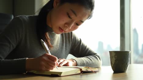 focused reflection: a young woman diligently writing in her journal while enjoying a warm beverage, capturing a moment of productivity and introspection
