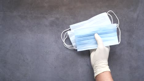 gloved hands holding masks on a gray surface