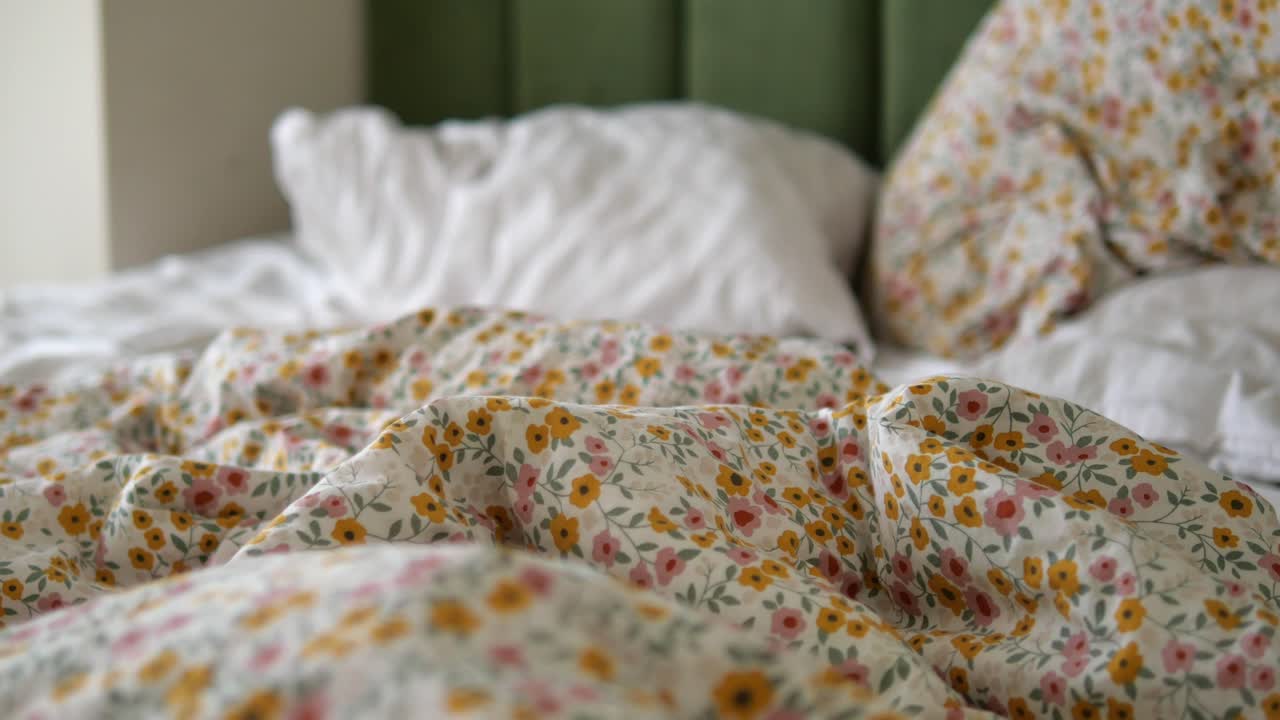 Letto accogliente e sfatto con piumone floreale e cuscini bianchi