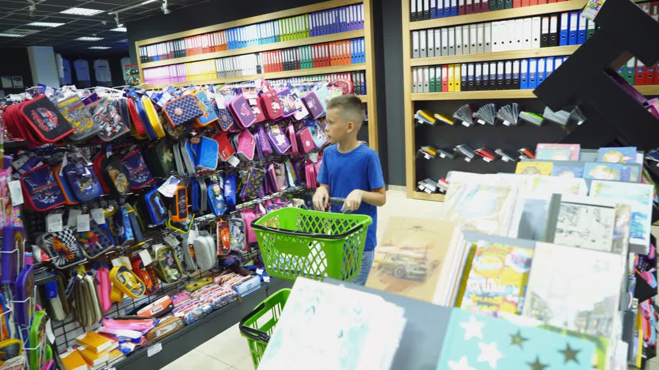 VINNITSA, UKRAINE - AUGUST 20, 2018: Beautiful boy choosing school stationery at a supermarket. Shopping for school