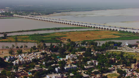 two bridges over the river aerial view, big canal starting from the river going between the city, farms and trees in the river, greenery and mountains of khyberpakhtunkhwa, pakistan