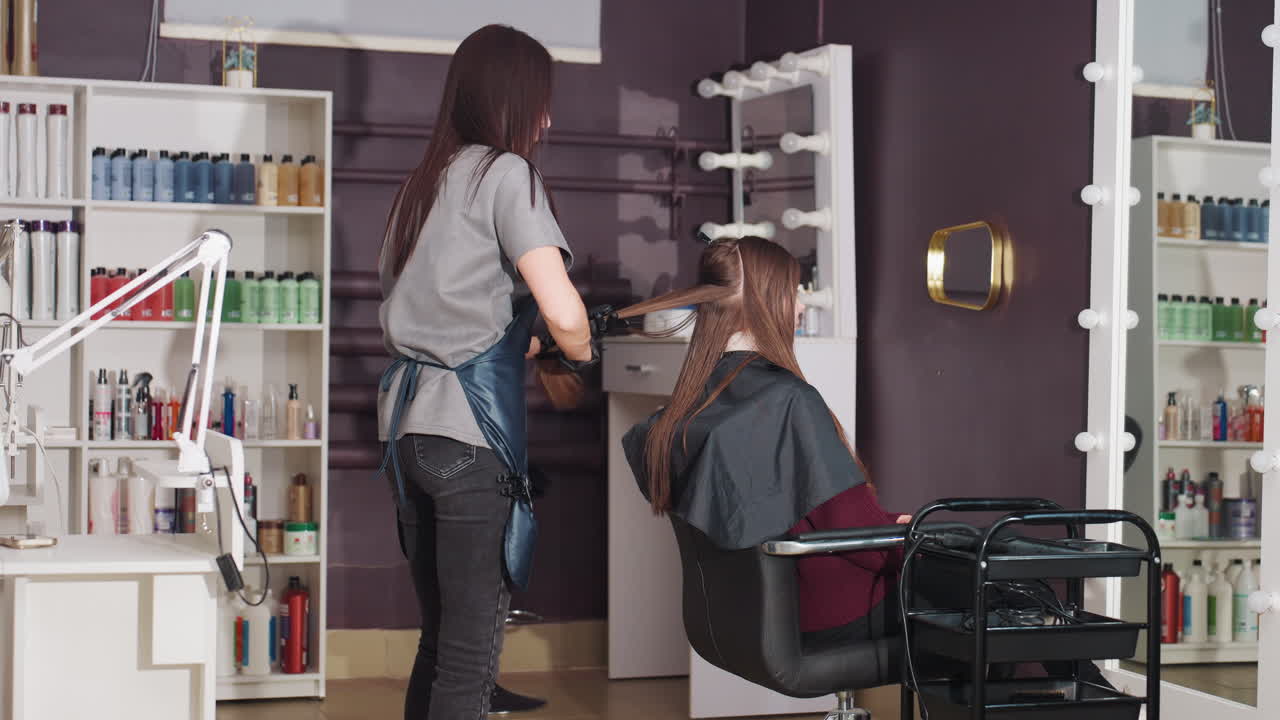 Parrucchiere chic impegnato a lavorare, parrucchieri attivi che creano abilmente acconciature alla moda nel salone, specialisti dei capelli professionisti impegnati nel processo di styling all'interno di un ambiente moderno del salone