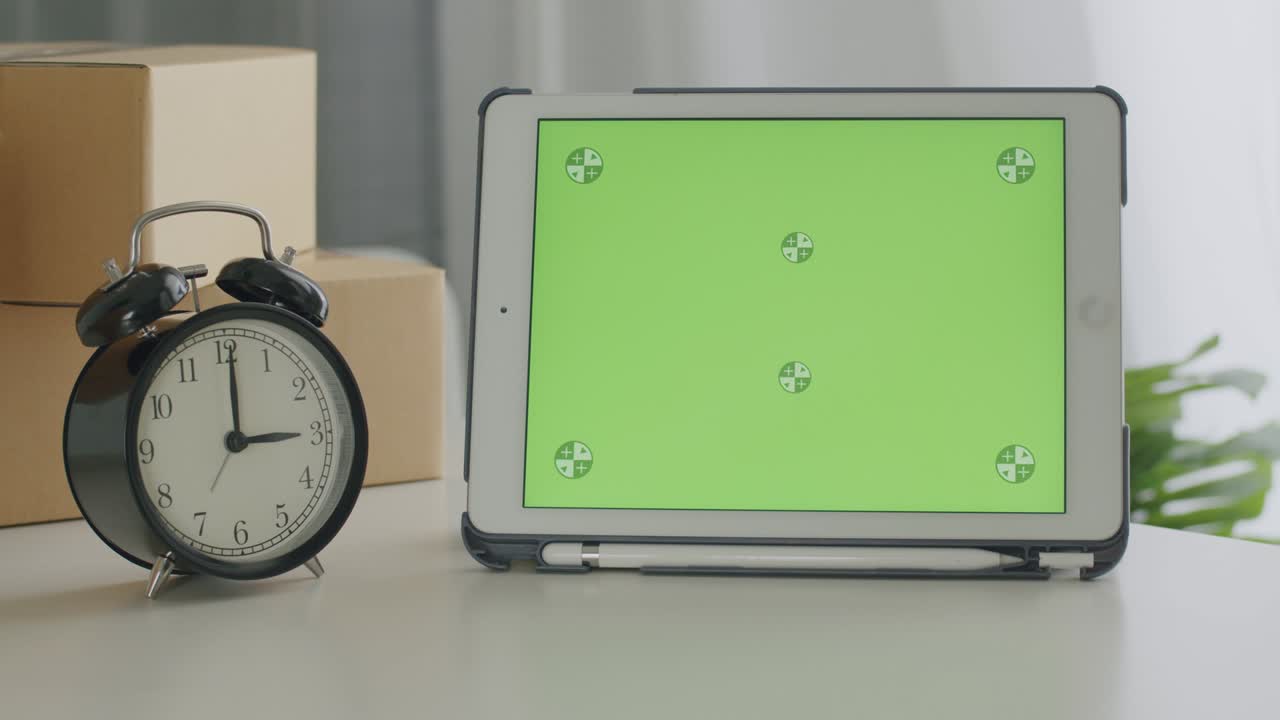 테이블 위에 빈 녹색 화면 크로마 키 템플릿이있는 태블릿과 홈 오피스에서 파셀 박스 배경이 있습니다.