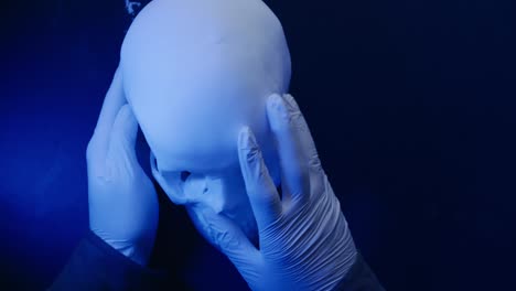 forensic anthropologist examines human skull under blue light pov