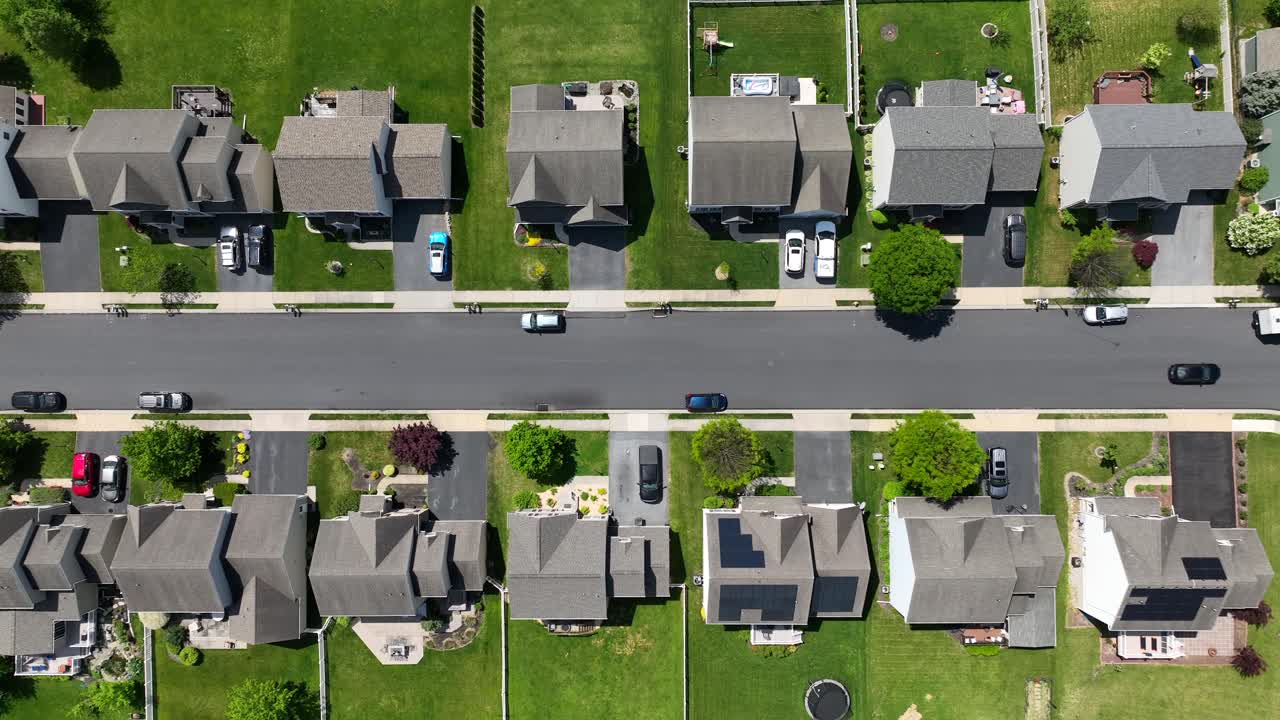 barrio suburbano de estados unidos que muestra casas bien alineadas, céspedes verdes y coches estacionados