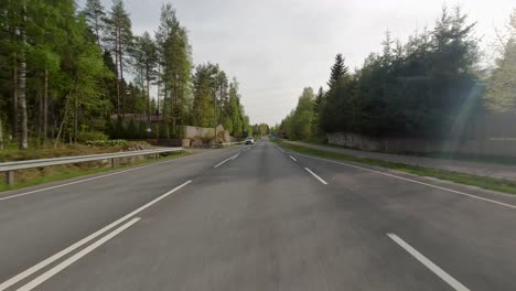 Cars-drive-along-the-road-with-green-grass-and-trees-visible-on-the-sides