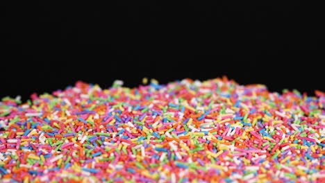 rainbow sprinkles cascade onto a black background