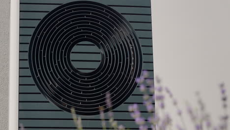 the external unit of the heat pump against the wall of a private house. lavender blooms in the foreground.