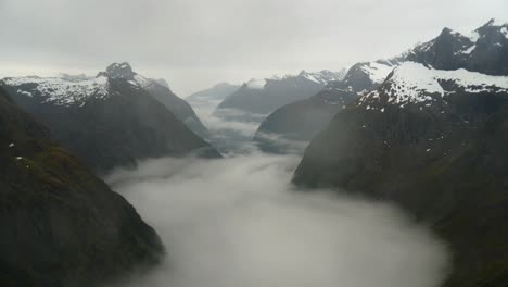 Toma-De-Timelapse-Que-Captura-El-Paisaje-Prístino-De-Gertrude-Saddle-En-El-Parque-Nacional-Fiordland-Con-Nubes-Brumosas-Formándose-Entre-El-Valle-Rocoso-En-Un-Día-Frío-Y-Lluvioso-Durante-La-Temporada-De-Invierno