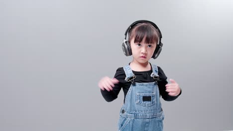 스튜디오에서 회색 배경에 청바지를 입고 헤드셋으로 음악을 듣는 아이