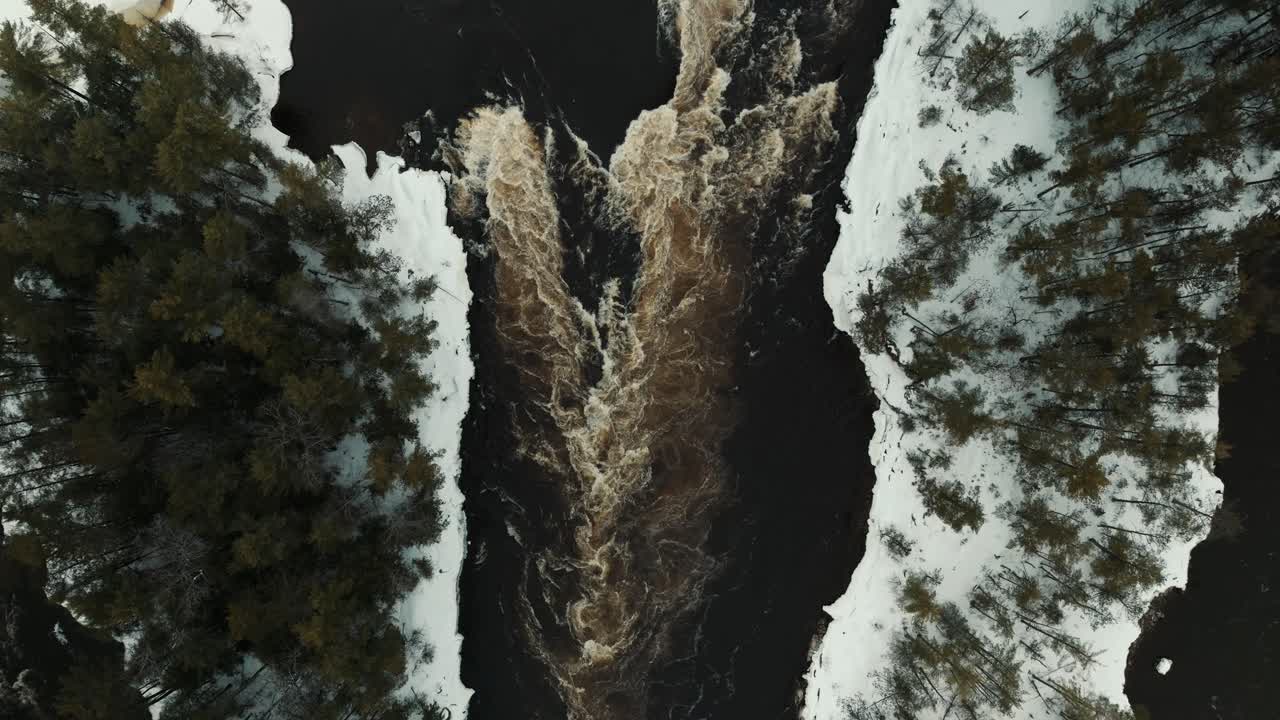 Top down drone shot of rapids on a fast moving river during winter in Ottawa Canada with snow and ice covering the banks