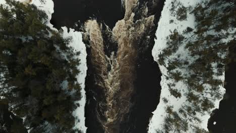 Drohnenaufnahme-Von-Oben-Nach-Unten-Von-Stromschnellen-Auf-Einem-Schnell-Fließenden-Fluss-Im-Winter-In-Ottawa,-Kanada,-Mit-Schnee-Und-Eis,-Die-Die-Ufer-Bedecken