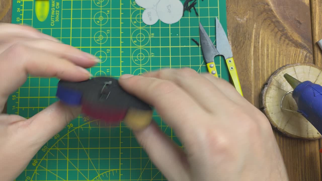 Women's hands demonstrate a felt brooch.