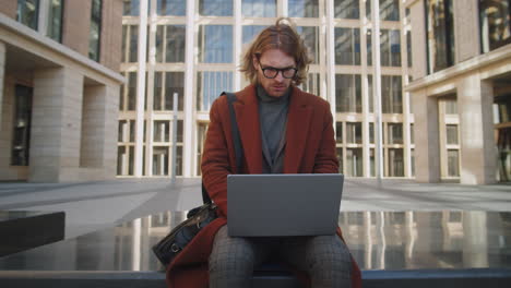 Elegante-Hombre-De-Negocios-Caucásico-Trabajando-En-Una-Laptop-Al-Aire-Libre