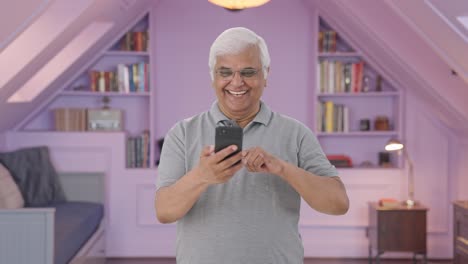 Happy-Indian-old-man-scrolling-through-phone