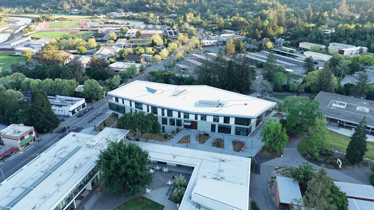 Aerial shot capturing the modern architecture of the Marin College buildings, surrounded by the lush, green landscape and residential neighborhood of Kentfield in Northern California on a sunny day