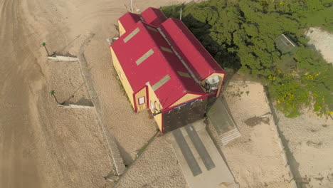 Rotierende-Drohne,-Die-Um-Die-Alte-Rettungsbootstation-Am-Sandstrand-In-Wells-next-the-sea-North-Norfolk-UK-Ostküste-Geschossen-Wurde