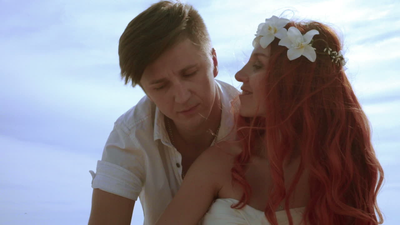 любящая пара целуется на небесном фоне. рыжая женщина целует своего мужа.