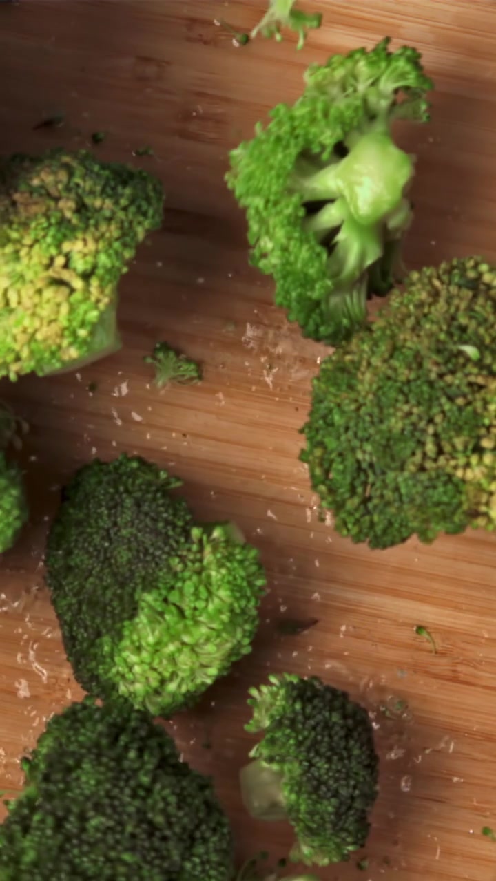 Cimette di broccoli freschi e verdi su un tagliere di legno che vanno a fuoco