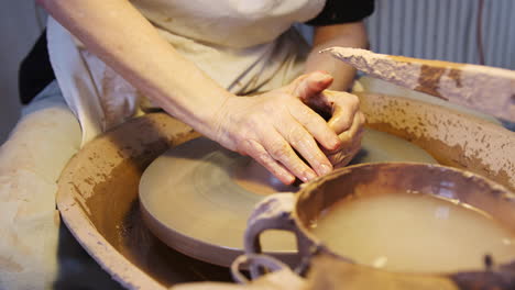 close up of male potter throwing clay for pot onto pottery wheel in ceramics studio