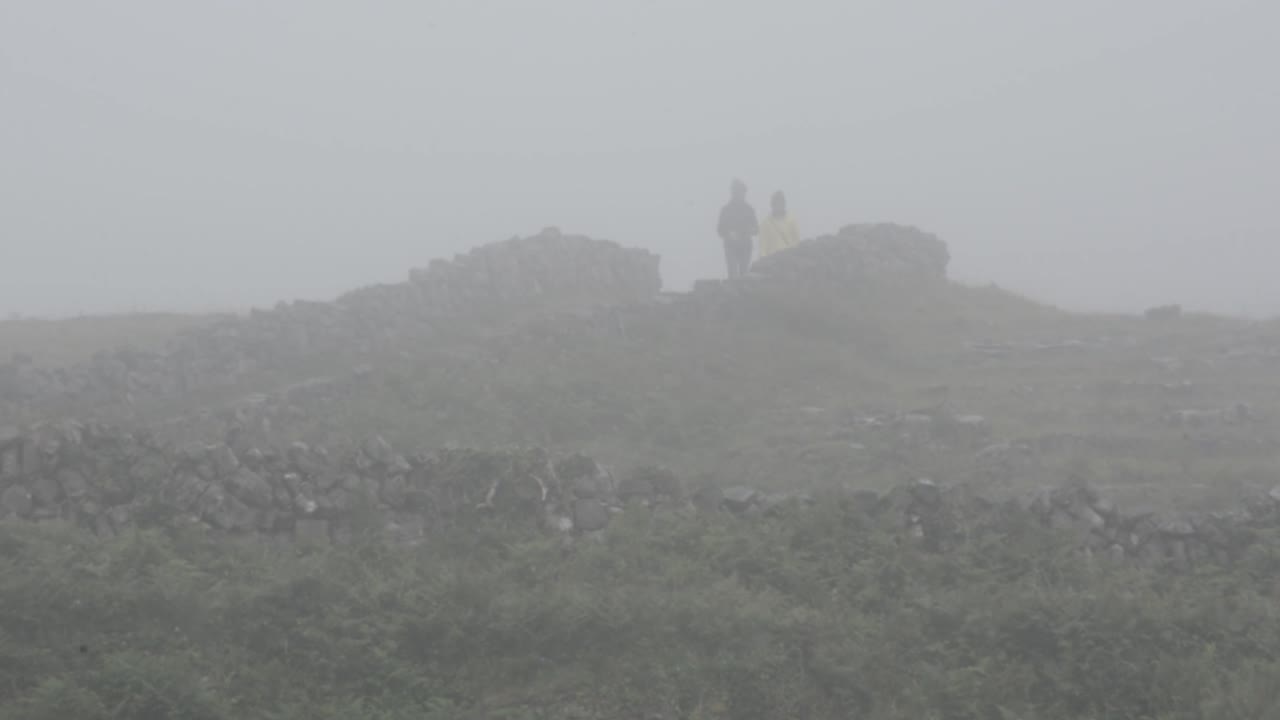 안개에서 벗어나 흐린 날의 등산로를 따라 걷는 사람들