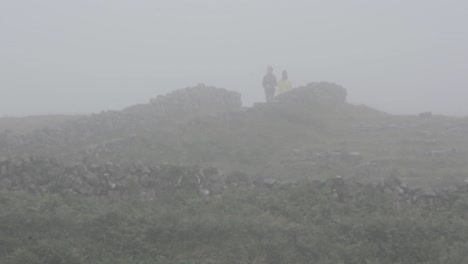 people emerging from fog and walking along hiking path of a cloudy day