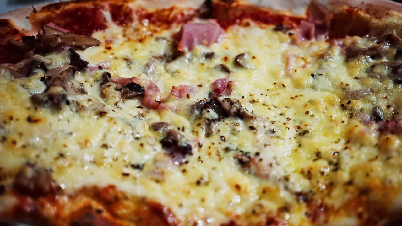 Close up of a pizza with ham and cheese on a table at a restaurant