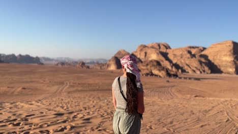 women in the desert of wadi rum in jordan during the day with wind blowing in her hair