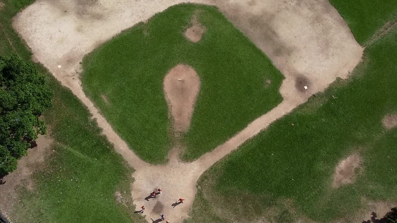 Un'inquadratura in boom di un campo da baseball nella Repubblica Dominicana con bambini che giocano a casa base.