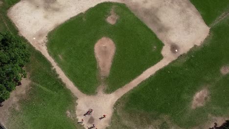 a boom shot of a baseball field in the dominican republic with kids playing in the home base