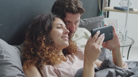 couple watching phone in bed