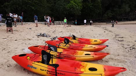 Colorful kayaks and people on a sandy beach
