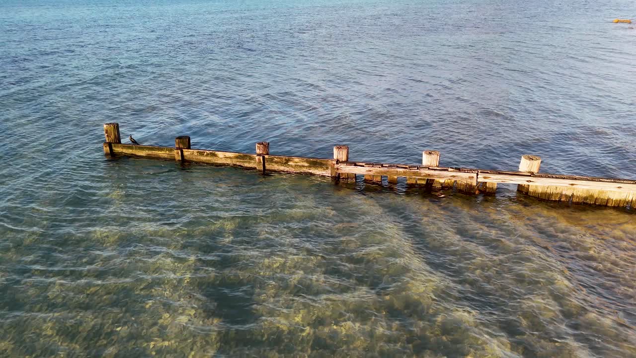 Waves interact with a wooden breakwater structure along the sea at Rye, Victoria, Australia