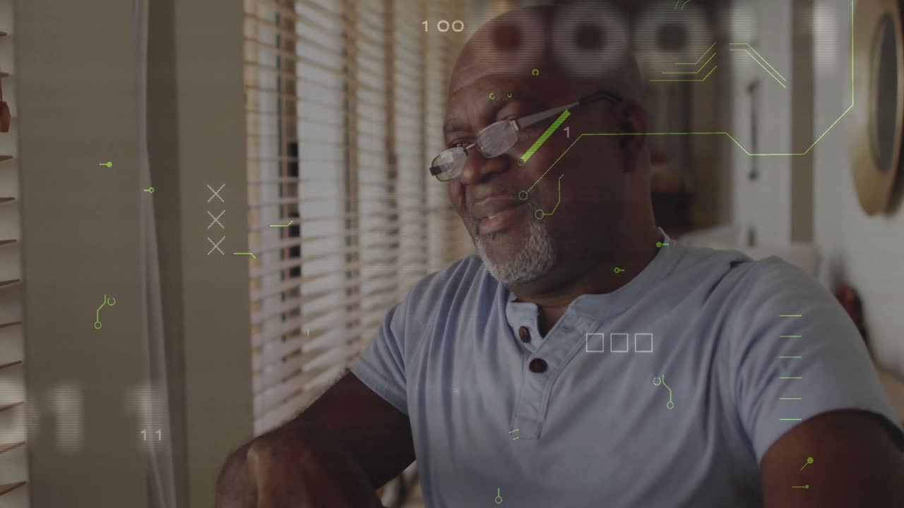 Senior man sitting by window using reading glasses in home study, showing data monitoring overlays