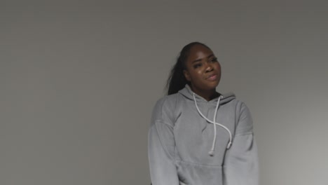 retrato de estudio de una mujer joven con capucha bailando con poca iluminación contra un fondo gris 2